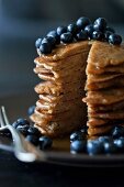 Stack of Apple spelt pancakes topped with maple syrup and fresh blueberries