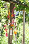 Blumendekoration in Campari-Fläschchen an Vintage Metallgestell aufgehängt