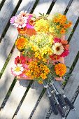 Posies of garden flowers next to vintage cutlery on weathered garden table