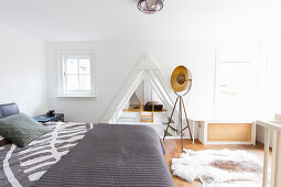 Double bed, studio lamp and cowhide rug in bedroom