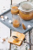 Toast with homemade caramel sauce for breakfast, served with spoon, jars and sugar cubes