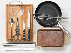 Various kitchen utensils: pan, spatula, brick, poultry shears, knives