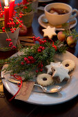 Plate of Christmas biscuits with name tag and posy of holly berries and juniper sprigs