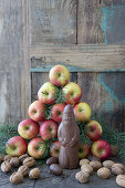 A homemade chocolate Santa Claus in front of a pyramid of apples and pine branches