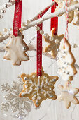 Weihnachtsbaum- und Schneeflockenplätzchen hängen mit roten Bändern auf Zweigen