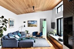 Lounge area with gray sofa set, window sill as bench and wooden ceiling