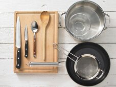 Verschiedene Küchenutensilien: Topf, Pfanne, Sieb, Messer, Löffel