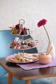 Wrapped sweets on cake stand, Gerbera daisy and sugar bowl on table