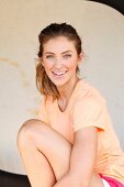 A young woman wearing an orange T-shirt in front of a light background