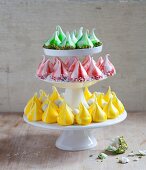 A cake stand with three different coloured meringue kisses