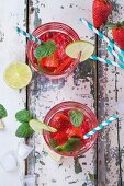 Selbstgemachte Erdbeerlimonade serviert mit Minze und Limetten in Gläsern (Aufsicht)