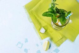 Glass of Iced green tea with lime, lemon, mint and ice cubes on green textile napkin