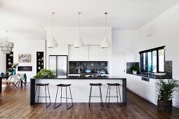 Elegant open kitchen with island, bar stools, dining area with classic chairs in the background