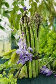 A bunch of green asparagus decorated with wisteria and lady's mantle
