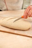 Bread dough being scored with a knife