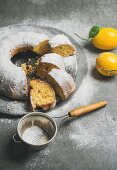 Homemade gluten-free lemon bundt cake with sugar powder over grey concrete background
