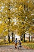 Zwei Kinder laufen Hand in Hand durch den Herbstwald