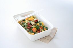 A vegetable and tofu dish in a takeaway box