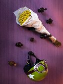 Various wooden pegs on wall holding old green motorcycle helmet and bunch of yellow flowers