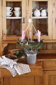 Wreath of candles hung from stick in bucket on four yellow ribbons