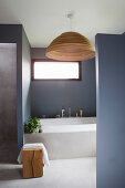 Blick auf Badewanne und Fenster im Badezimmer mit grauen Wänden