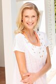 Blonde Frau in orangefarbenem Top und bestickter weißer Bluse mit Lochmuster