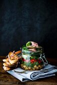 Lunch in a glass jar: chickpeas, green cabbage, lambs lettuce, burgundy ham, parsley jelly and toasted bread