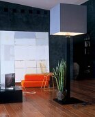 Standard lamp with cubist lampshade in front of orange floor cushions and modern artwork