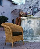 Wicker chair with seat cushion in front of vintage fountain in Mediterranean courtyard