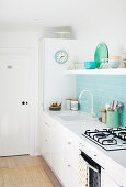 Helle Küche mit hellblau gefliestem Spritzschutz und offenem Regal