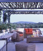 Wicker furniture and arrangement of candles on terrace at twilight