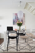 White table and black and transparent chairs on pale rug in dining area