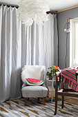 Watermelon-slice cushion on retro armchair in front of grey curtain