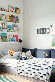 Books arranged on narrow shelves above bed in child's bedroom