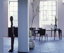 Black dining table in loft apartment with industrial windows and stone floor