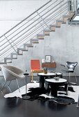 Designer chairs, floating staircase and concrete wall