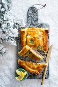 Fish pie on a chopping board in the snow at Christmas