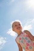 Blue sky and a little girl wearing a swimming costume