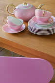 Pink tea service stacked on wooden table