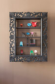 Miniature designer chairs in display cabinet with black frame