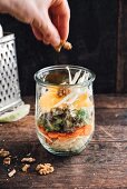Veganer Salat mit Weisskohl, Karotten, Blattsalat, Fenchel, Orangen und Walnüssen im Glas