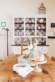 Rustic wooden dining table and white lacquered sideboard in the dining room