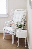 White painted rattan chair and side table with bouquet and necklace from Bali in the corner of the room