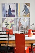 Esstisch mit Marmorplatte und verschiedenen Stühlen vor moderner Malerei mit Frauenmotiven