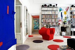 Round rugs, red armchair and traditional fireplace surround in eclectic living room