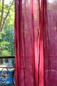 Red curtain in front of vintage-style balcony balustrade