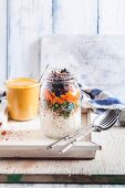 Rice salad in a glass jar with mung bean seedlings, peas, carrots and rosemary with a Thai peanut and chilli sauce (Vegan)