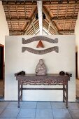 Buddha statue on antique wooden table against partition wall