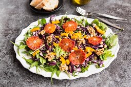 A salad platter with quinoa, chickpeas, yellow pepper, walnuts, red cabbage and blood orange