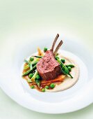A rack of lamb with ginger jus, bean purée and spring vegetables